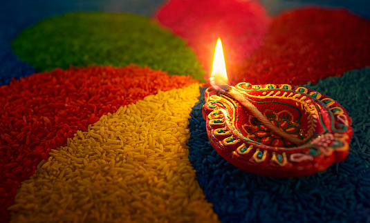 Diwali oil lamp - Diya lamp lit on colorful rangoli